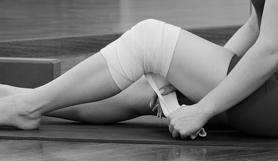 Focused on Recovery: Wrapping a Knee with an Elastic Bandage. The Art of Injury Care on a Yoga Mat