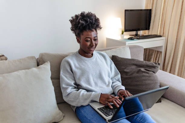 istock Shot of a young woman using a laptop while relaxing on a sofa at home. 2112100156