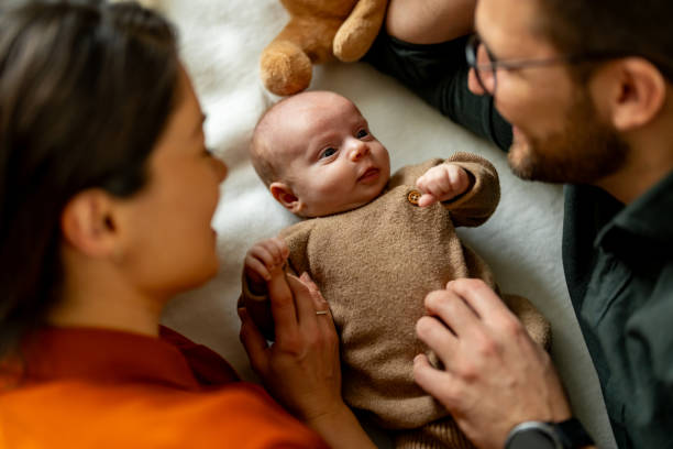 Happy parents playing with their newborn son on bed