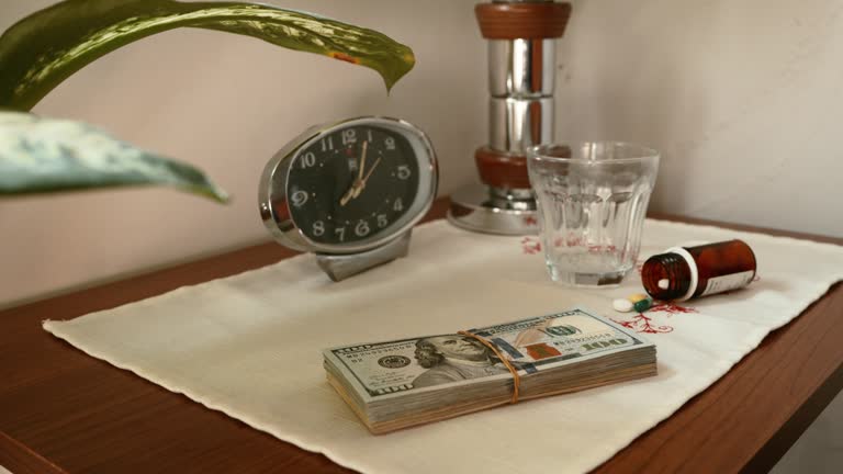 Stack of US dollar banknotes and drugs on night stand