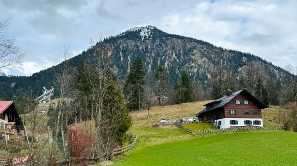 Oberstdorf, Germnay - March 3rd - 2024: typical house on the right side and the Schattenberg  ski jump  in the left background.