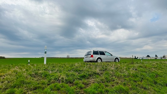 Marbach, Germany - March, 21st - 2024: Car with combustion engine under dramatic gray sky driving on a rural road.