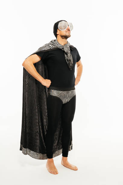 A man poses in a superhero-inspired black and white insect costume in a studio setting.