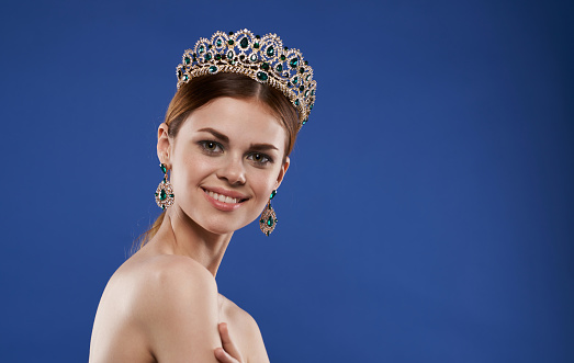 Bride holding luxurious crown on blurred background, closeup view