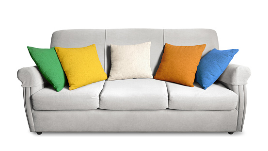 A light gray three seater sofa with armrests and five colored cushions isolated on a blank empty background.