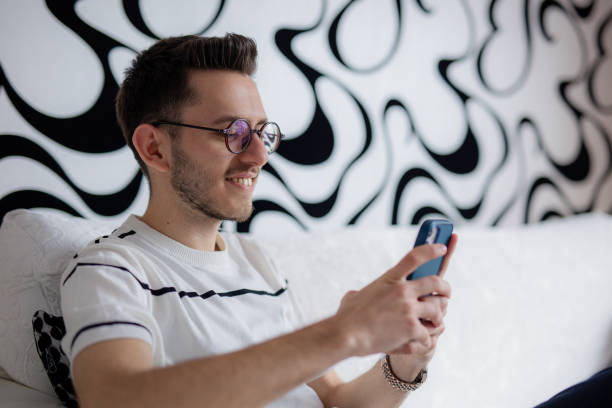 istock a young bearded man sitting on the couch is spending time with his phone 2112175403
