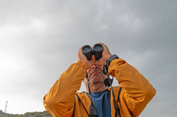 istock A man birdwatching with binoculars on a lake. 2112191820
