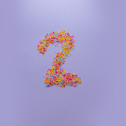 Number two made of sugar sprinkles on a purple background. Creative alphabet concept.