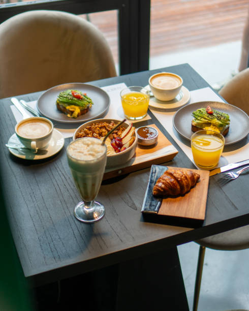 istock Complete breakfast table for two with coffee, juice, croissants, avocado toasts and yogurt 2112209697