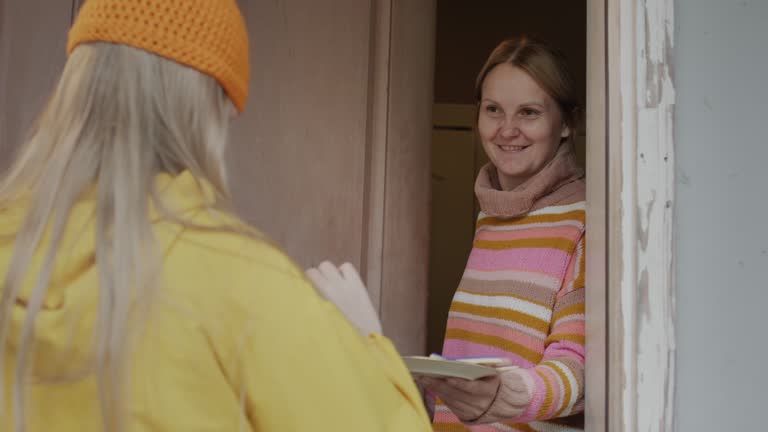 The child comes to get candy at the door of the house. Woman opens the door and gives a treat