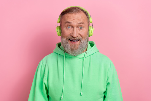 Photo of excited funky guy dressed green hoodie listening songs headphones isolated pink color background.