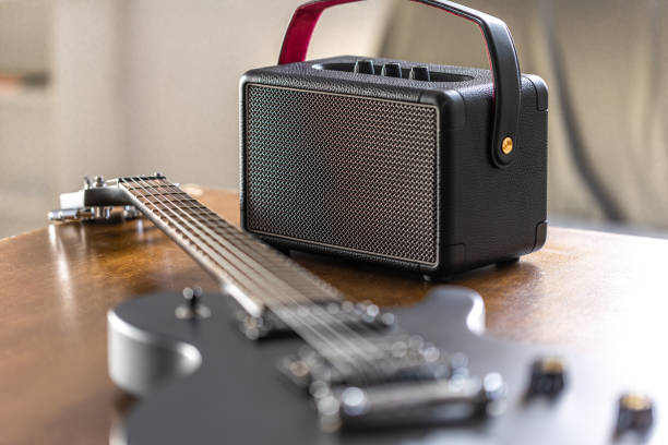 istock Black electric guitar and speaker on a wooden table. 2112224126