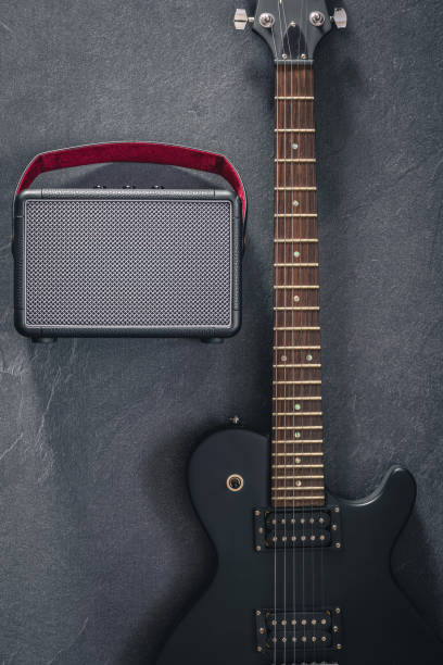 istock Electric guitar and speaker on a textured black background, top view. 2112224132