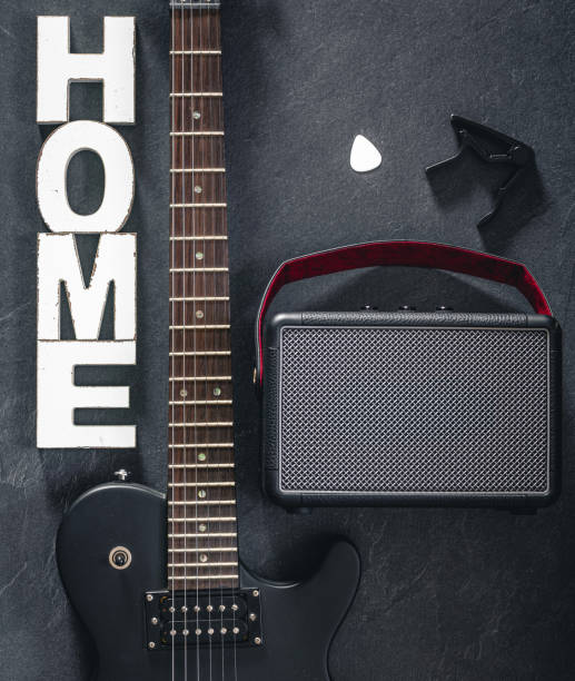 istock Electric guitar and amplifier on a dark background with decorative word Home. 2112224141