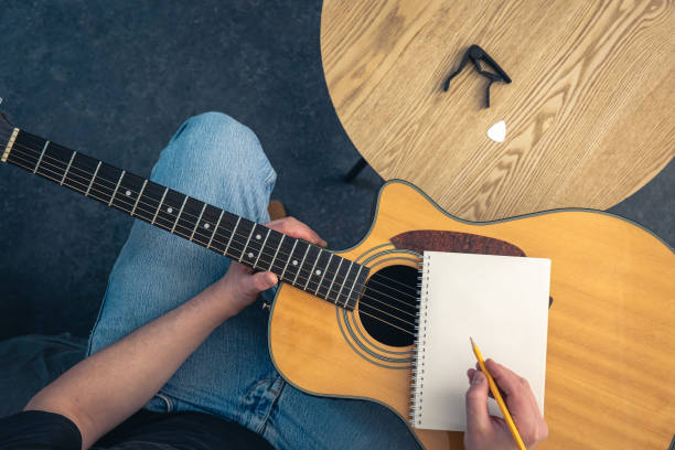 istock A man with a guitar writes in a blank notebook, top view. 2112227655