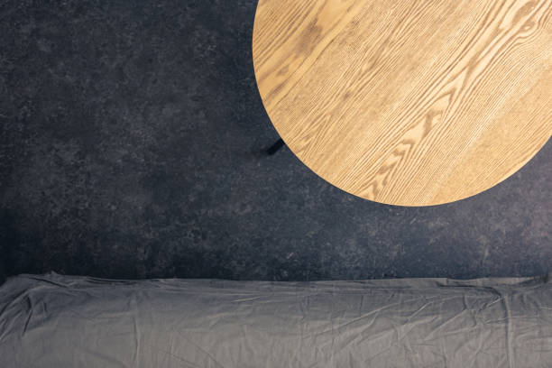 Wooden table and sofa on a dark floor, top view. Minimalistic background, space for text.