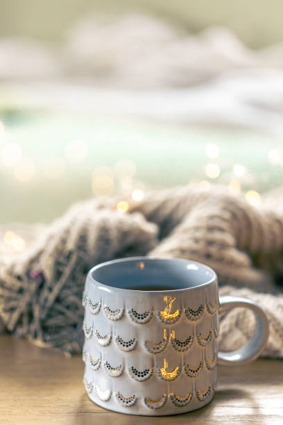 Close-up, shiny gray cup on a blurred background with a knitted element. Home composition with a cup of hot drink.
