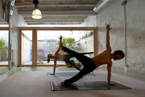 istock Flexible woman and man doing yoga in Side Plank Star pose 2112232710