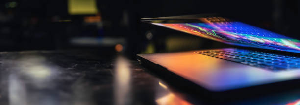 istock A laptop half closed in the dark with colorful glow. 2112247129