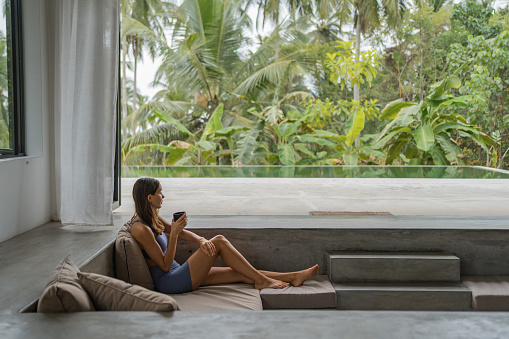 Young woman relaxes in outdoor living room with jungle in distance