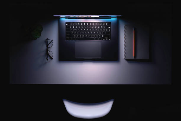 istock An open laptop with a glowing screen and a notepad on the table at night. 2112251637
