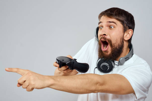 istock Man with gamepad headphones playing leisure technology white t-shirt light background 2112251655