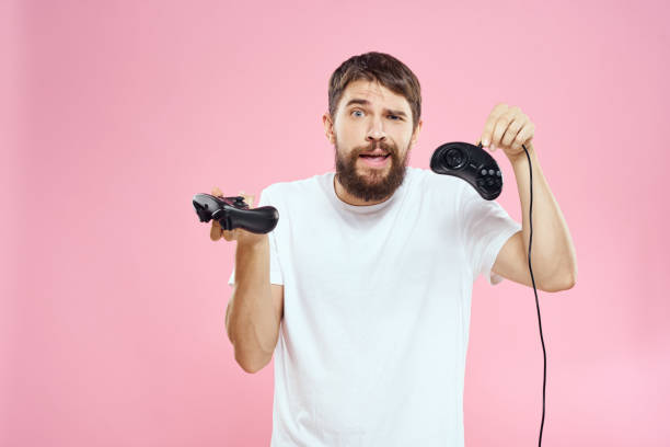 istock Man with two joysticks in hands fun game technology lifestyle pink background 2112260980