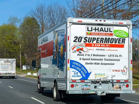 A U-Haul truck displaying vibrant advertising for the company moves through a suburban road. Charlotte, North Carolina, USA. 03/25/2024.