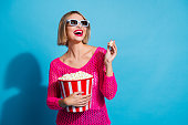 Photo portrait of pretty young girl eat popcorn look empty space dressed stylish pink knitwear outfit isolated on blue color background