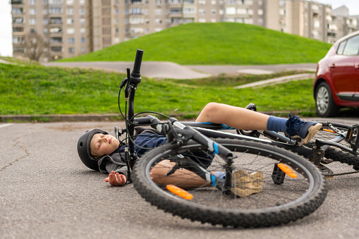 Little boy lying on asphalt after falling from the bike