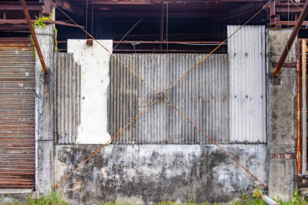Wall of an old warehouse clad with corrugated asbestos cement sheets and with repairs of corrugated and rusty metal sheets the city of Sabang which in the main city on the island Weh north of Sumatra