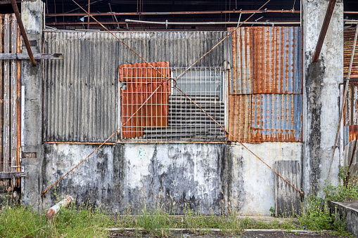 Wall of an old warehouse clad with corrugated asbestos cement sheets and with repairs of corrugated and rusty metal sheets the city of Sabang which in the main city on the island Weh north of Sumatra