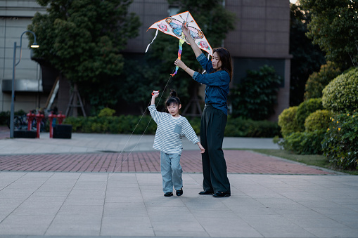 An Asian mother teaches her daughter how to fly kites