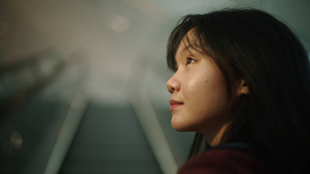 istock Teenage standing on escalator moving up. 2112324939