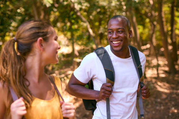 istock Young Active Couple Wearing Backpacks Hiking Along Trail Through Countryside 2112338105