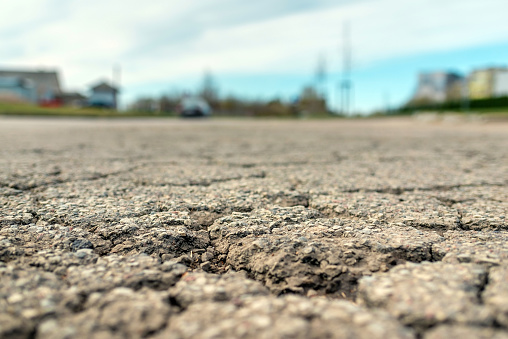 Empty damaged alphalt road in the street.Blurred blue sky background.Selective focus,Close-up.