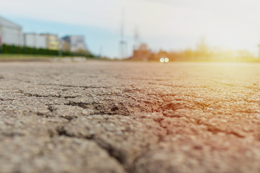 Empty damaged alphalt road in the sunny street.Blurred blue sky background.