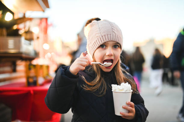 istock child eating whipped cream at Christmas market. 2112378921