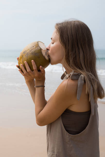 istock woman drinking fresh coconut water on the beach 2112407414