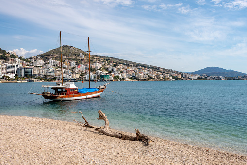 Driftwood on the beach and a yacht in Saranda, Albania