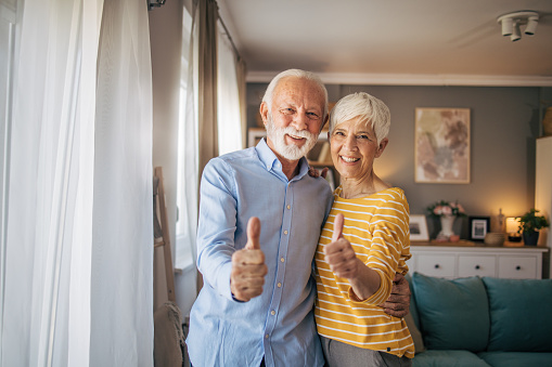 Senior beautiful couple standing together smiling and showing thumb up symbol with hands