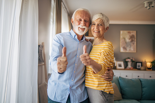 Senior beautiful couple standing together smiling and showing thumb up symbol with hands