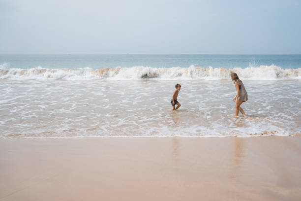 istock Young mother plays with her son in sea waves 2112472364