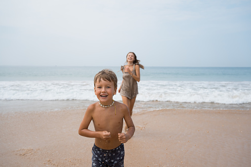 Happy beautiful young mother and son running on beach. Summer vacation of mother and son in tropical country