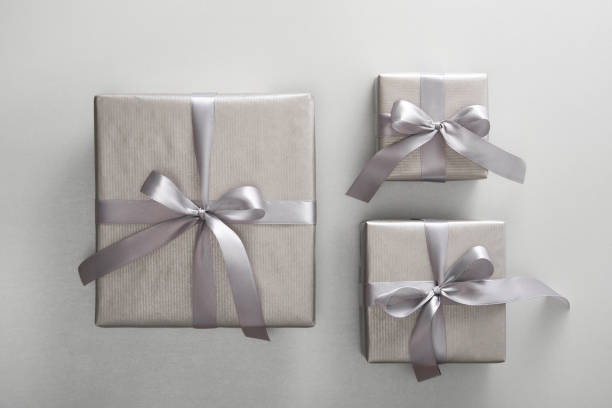 istock Set of monochrome silver gift boxes with gray ribbons on light background. 2112485442