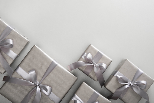Monochrome gray gift boxes with gray ribbons on light background. Place for your text.