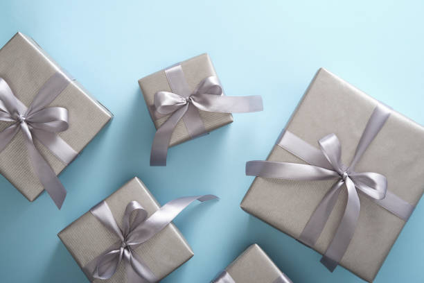 istock Set of monochrome silver gift boxes with gray ribbons on light blue background. 2112486486