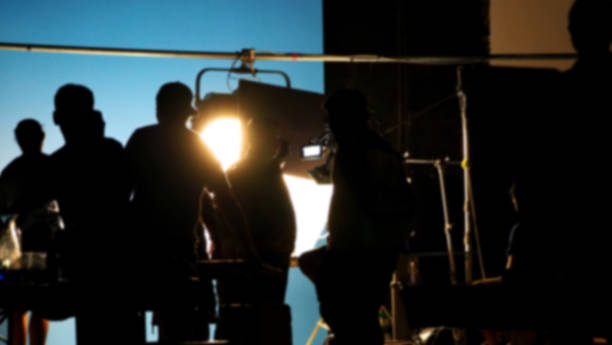 istock Blurry images of making video production shooting studio in silhouette which have professional equipment such as camera, tripod and blue screen backdrop set for chroma key technique in post process 2112491172
