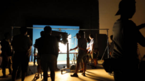 istock Blurry images of making video production shooting studio in silhouette which have professional equipment such as camera, tripod and blue screen backdrop set for chroma key technique in post process 2112491173