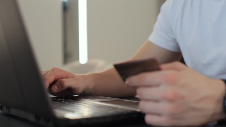 Close-up of man hands pressed the credit card code to pay online via the laptop. Commerce lifestyle concept, purchase transaction.